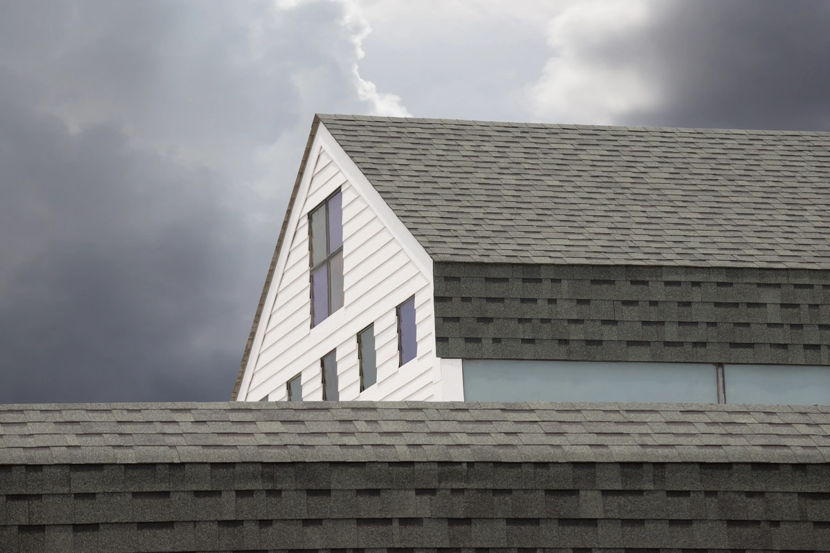 asphalt shingle roof with dark clouds behind