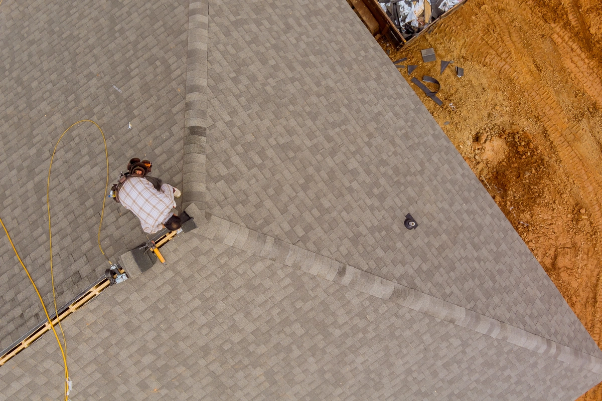 aerial view of worker installing new shingles on roof