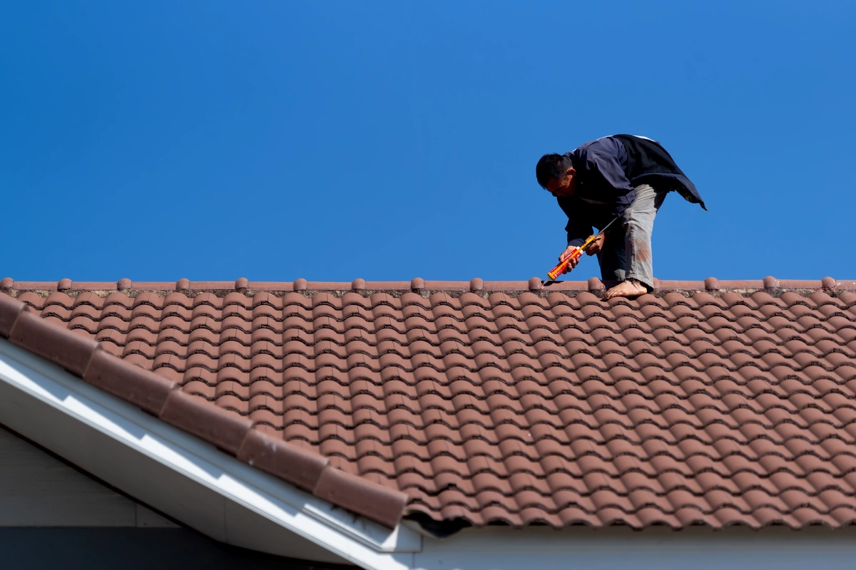 man sealing roofing tiles for roof leak