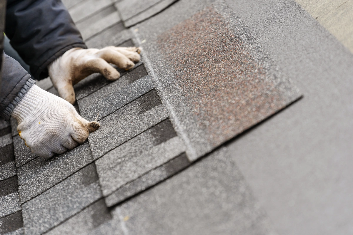 hands installing asphalt shingles. shingle roof repair