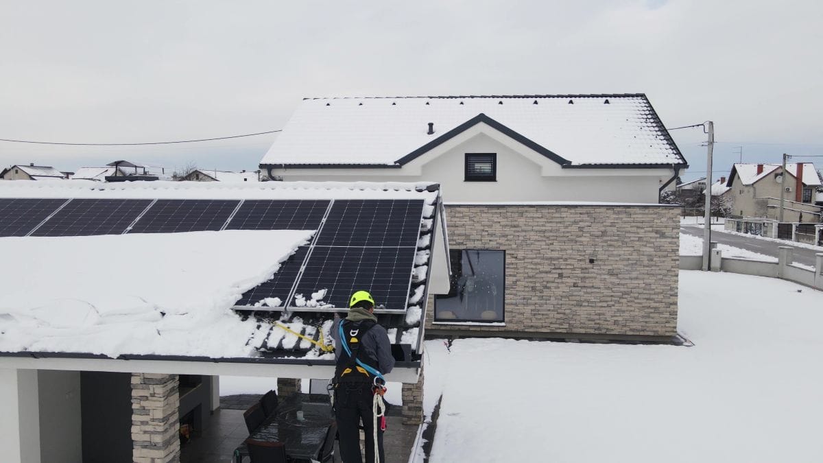 worker removing snow on top of roof